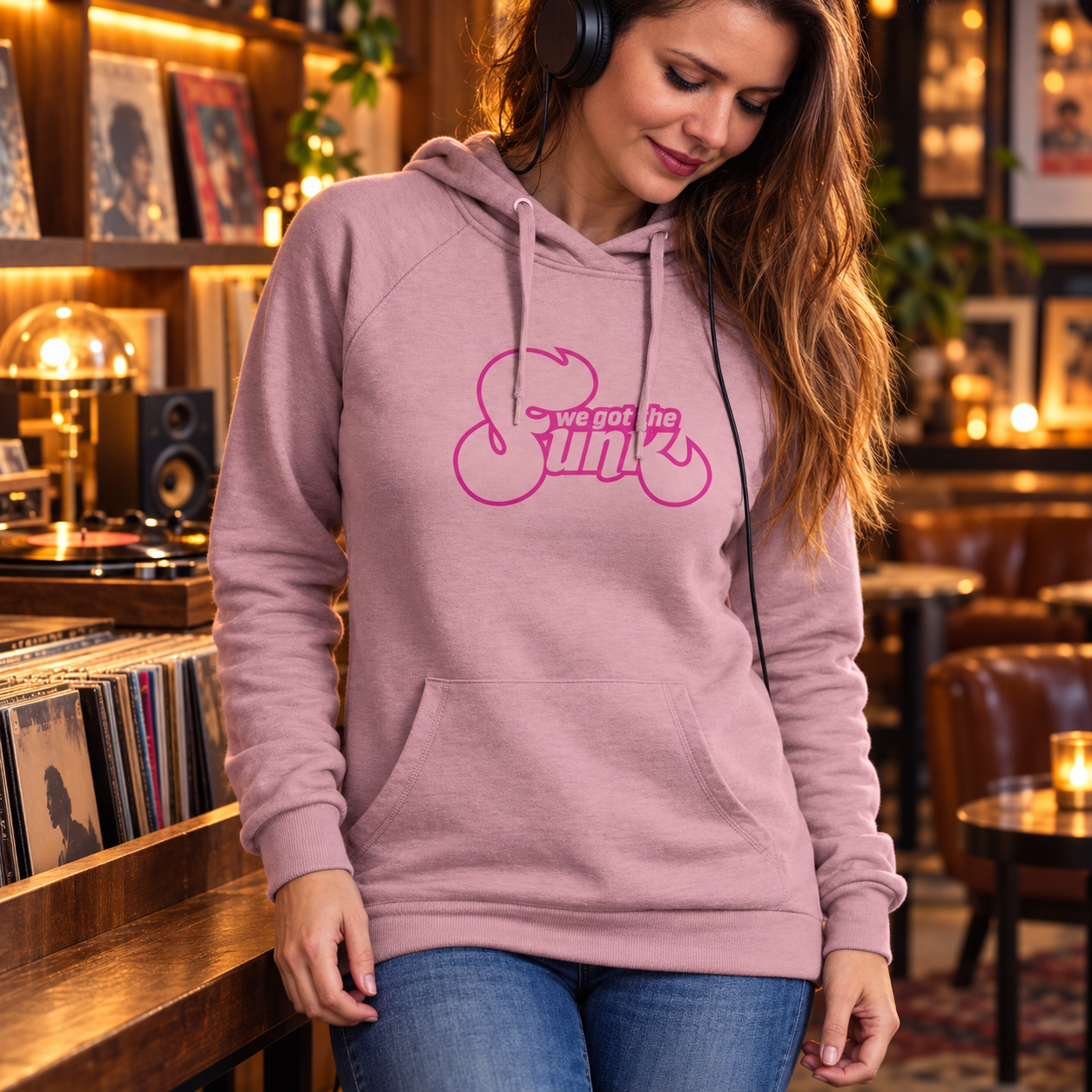 Woman listening to music in a vinyl bar wearing a mauve We got the Funk hoodie